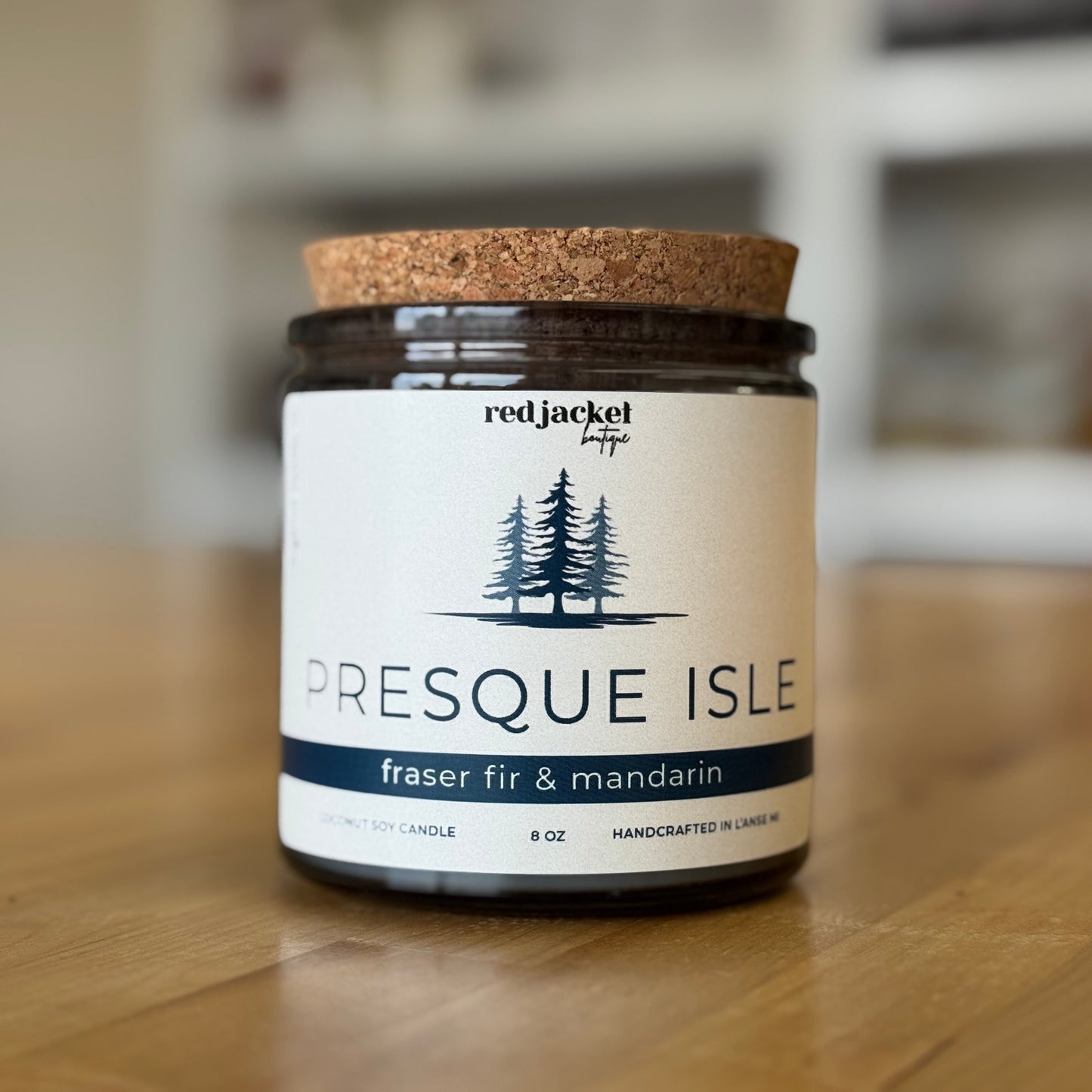 Candle jar with 'Presque Isle' label on a wooden surface