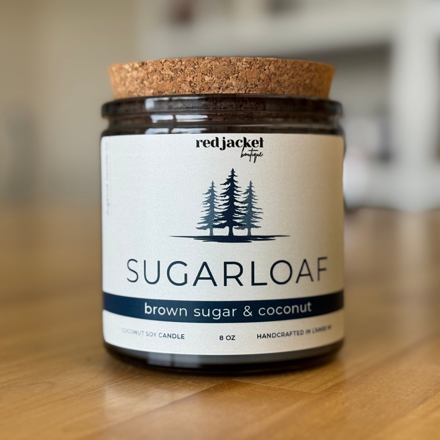 Scented candle 'Sugarloaf,’ brown sugar and coconut, with a cork lid on a wooden surface. 