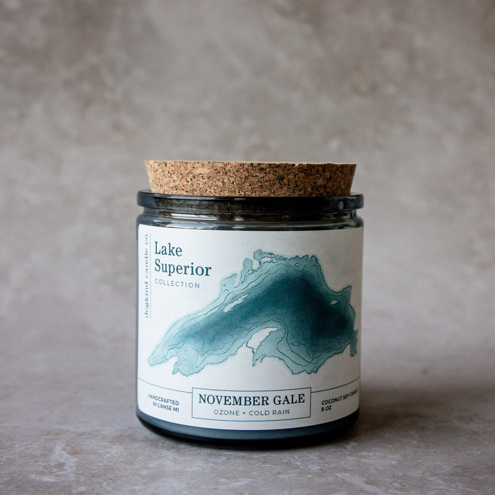 Scented candle with cork lid and 'Lake Superior november gale ozone and cold rain' fragrance label on a gray background