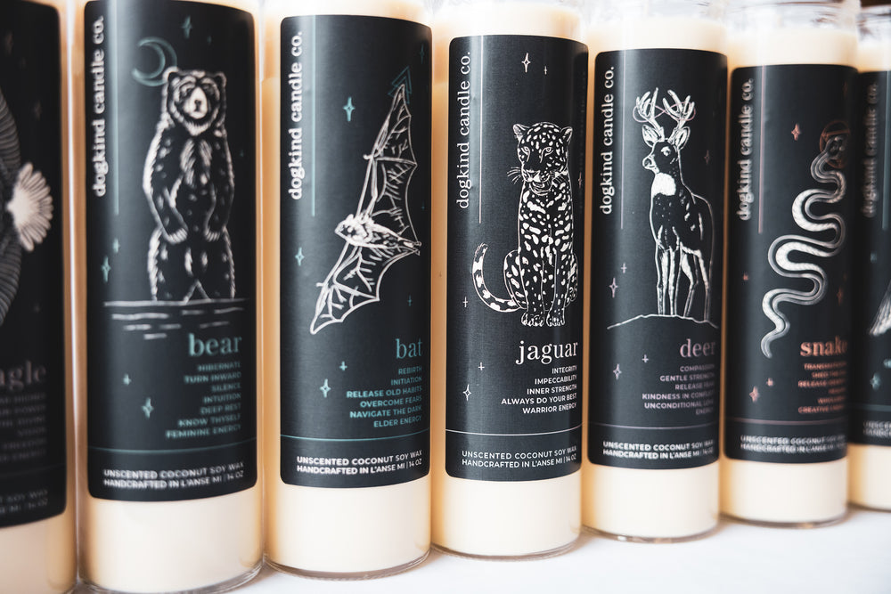 Row of unscented ceremony candles with animal medicine spirit animal illustrations on black labels on 7-day clear glass candle jars.