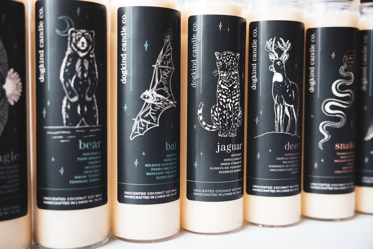Row of unscented ceremony candles with animal medicine spirit animal illustrations on black labels on 7-day clear glass candle jars.