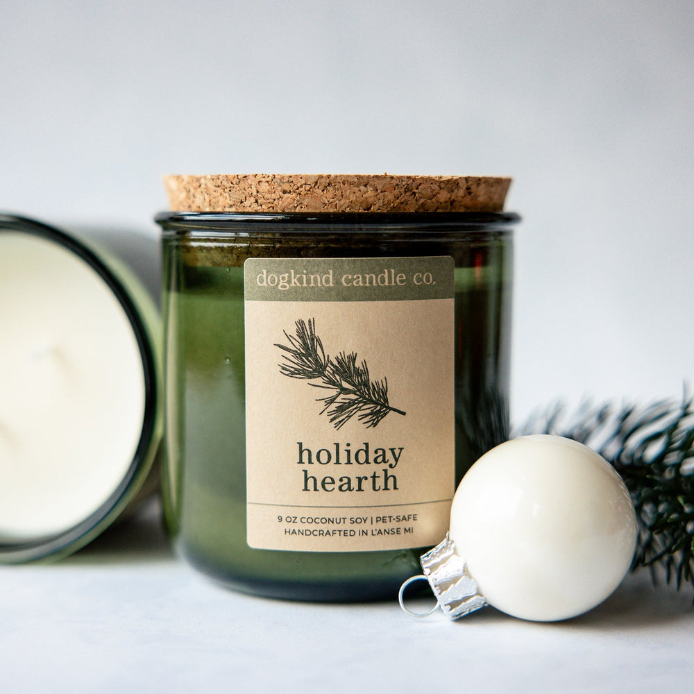 
                  
                    Holiday Hearth  holiday scented candle from Dogkind Candle Co. on a textured surface with pine greenery and Christmas ornament in the background.
                  
                