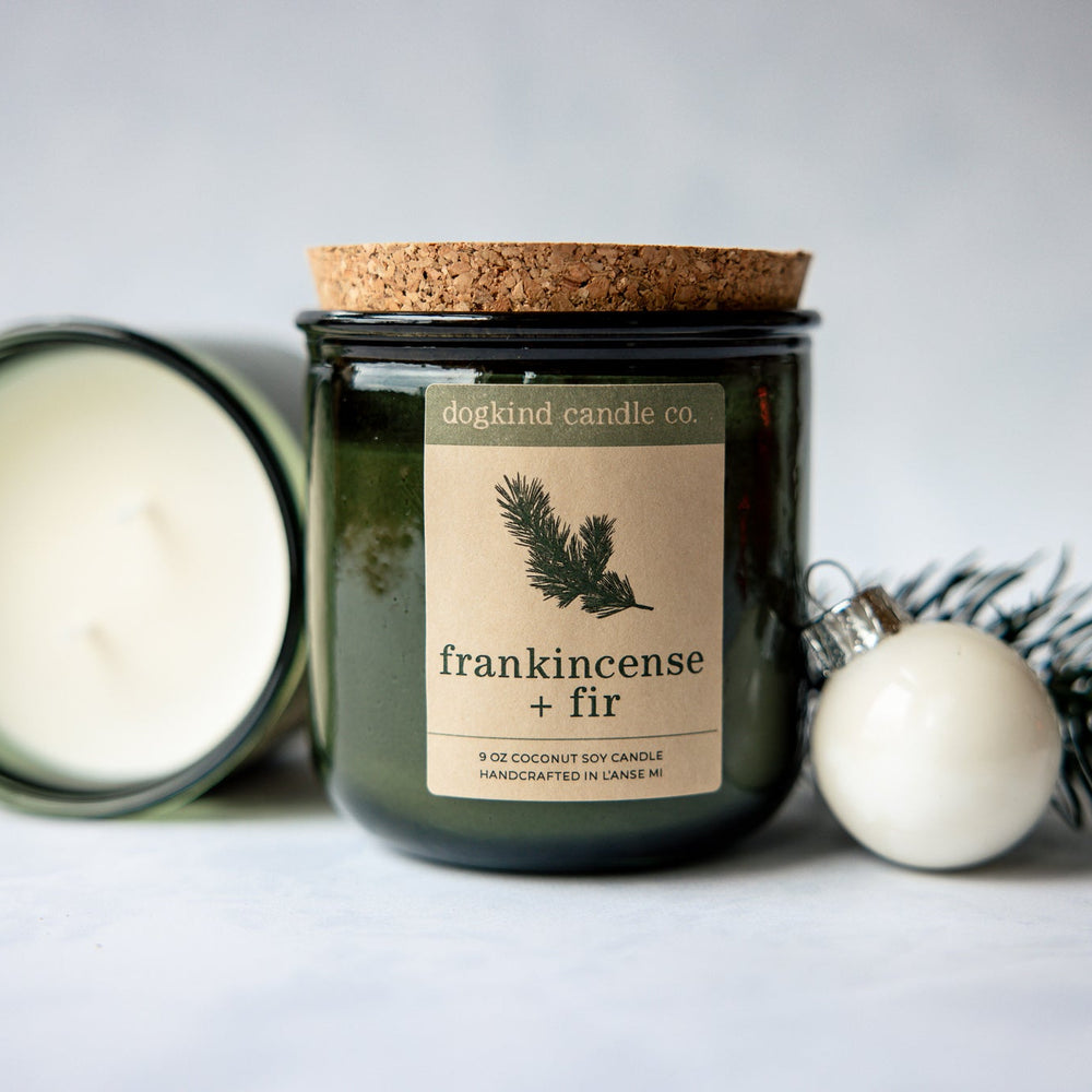 
                  
                    Frankincense + Fir  holiday candle from Dogkind Candle Co. on a textured surface with pine greenery and Christmas ornament in the background.
                  
                