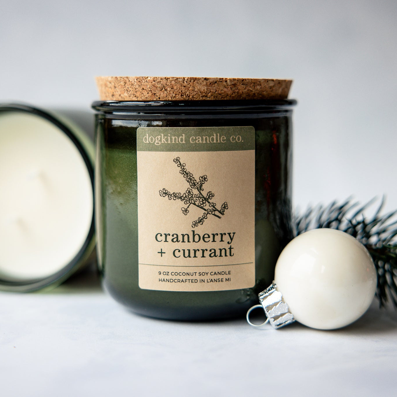 
                  
                    Cranberry Currant  holiday candle from Dogkind Candle Co. on a textured surface with pine greenery and Christmas ornament in the background.
                  
                