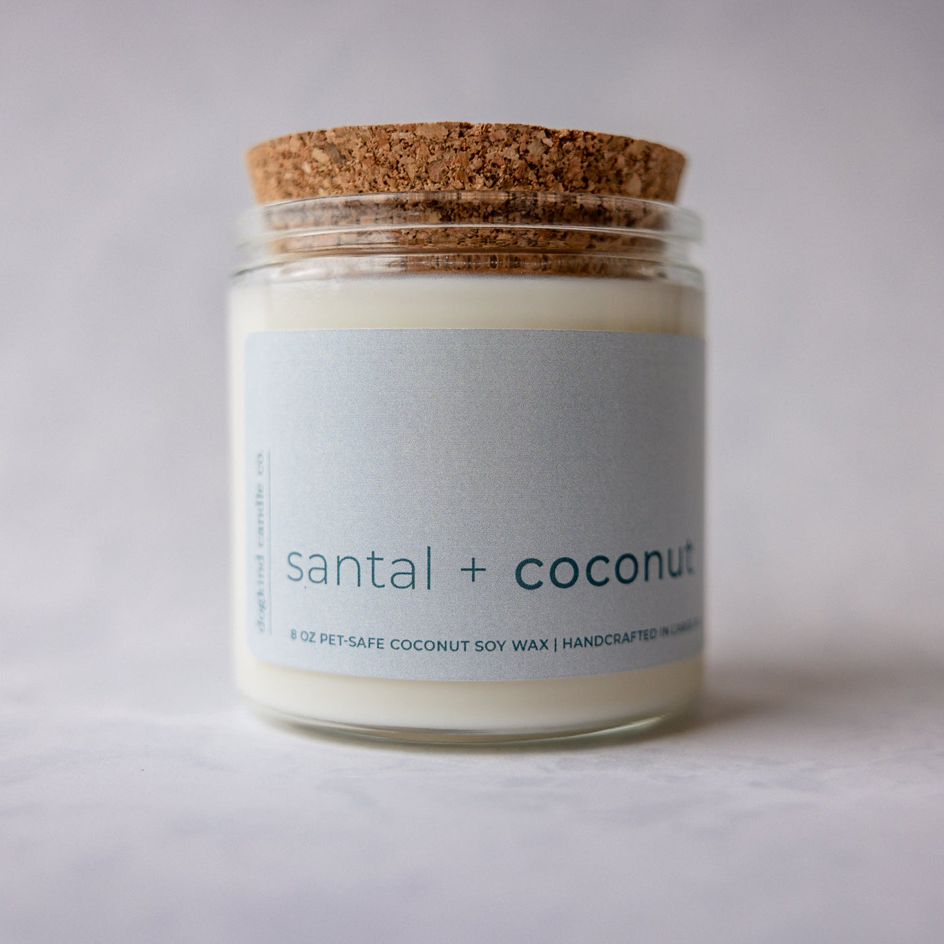 
                  
                    Candle jar labeled 'santal + coconut' with a cork lid on a light background
                  
                