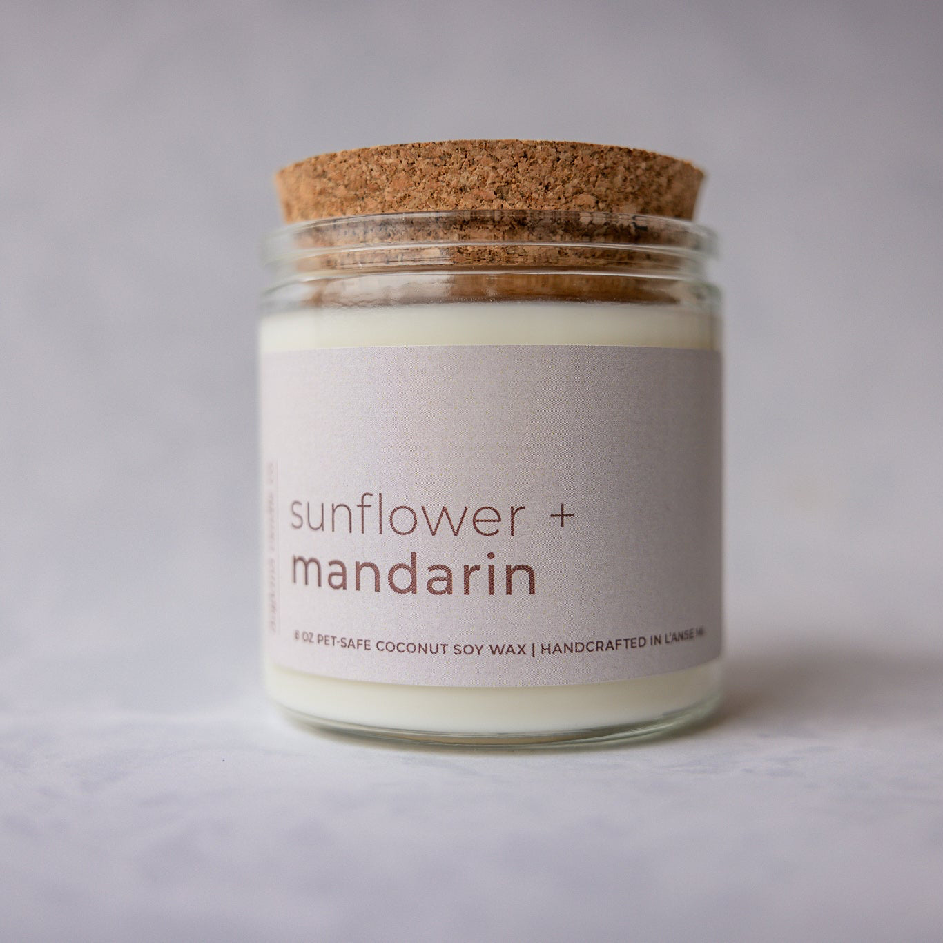 
                  
                    Candle jar with cork lid labeled 'sunflower + mandarin' on a light gray background
                  
                