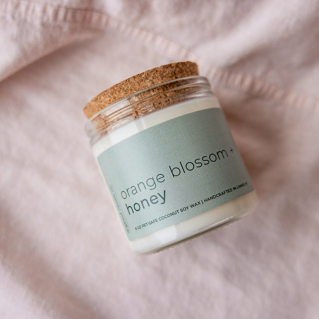 
                  
                    Jar of 'Orange Blossom Honey' on a soft pink fabric background
                  
                