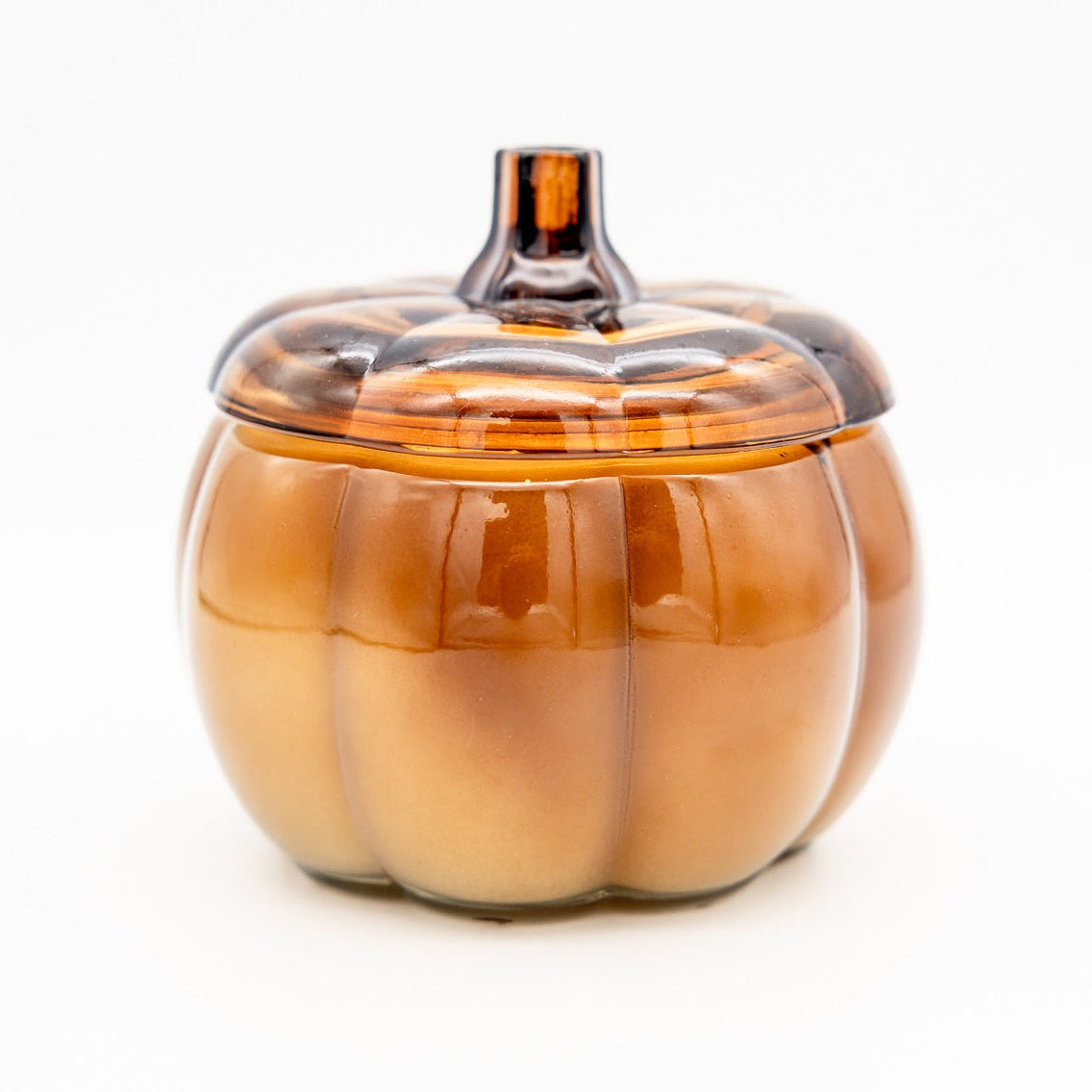 An amber glass pumpkin-shaped lidded container with a ribbed body and stem, photographed on a clean white background.
