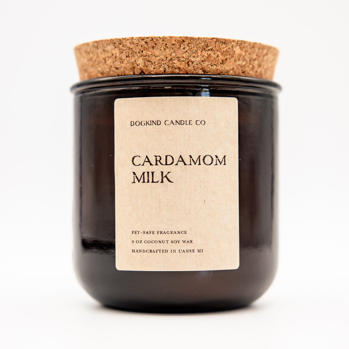 
                  
                    A Dogkind Candle Co. 'Cardamom Milk' coconut soy wax candle in a dark amber glass jar with a cork lid and a beige paper label, set against a plain white background.
                  
                