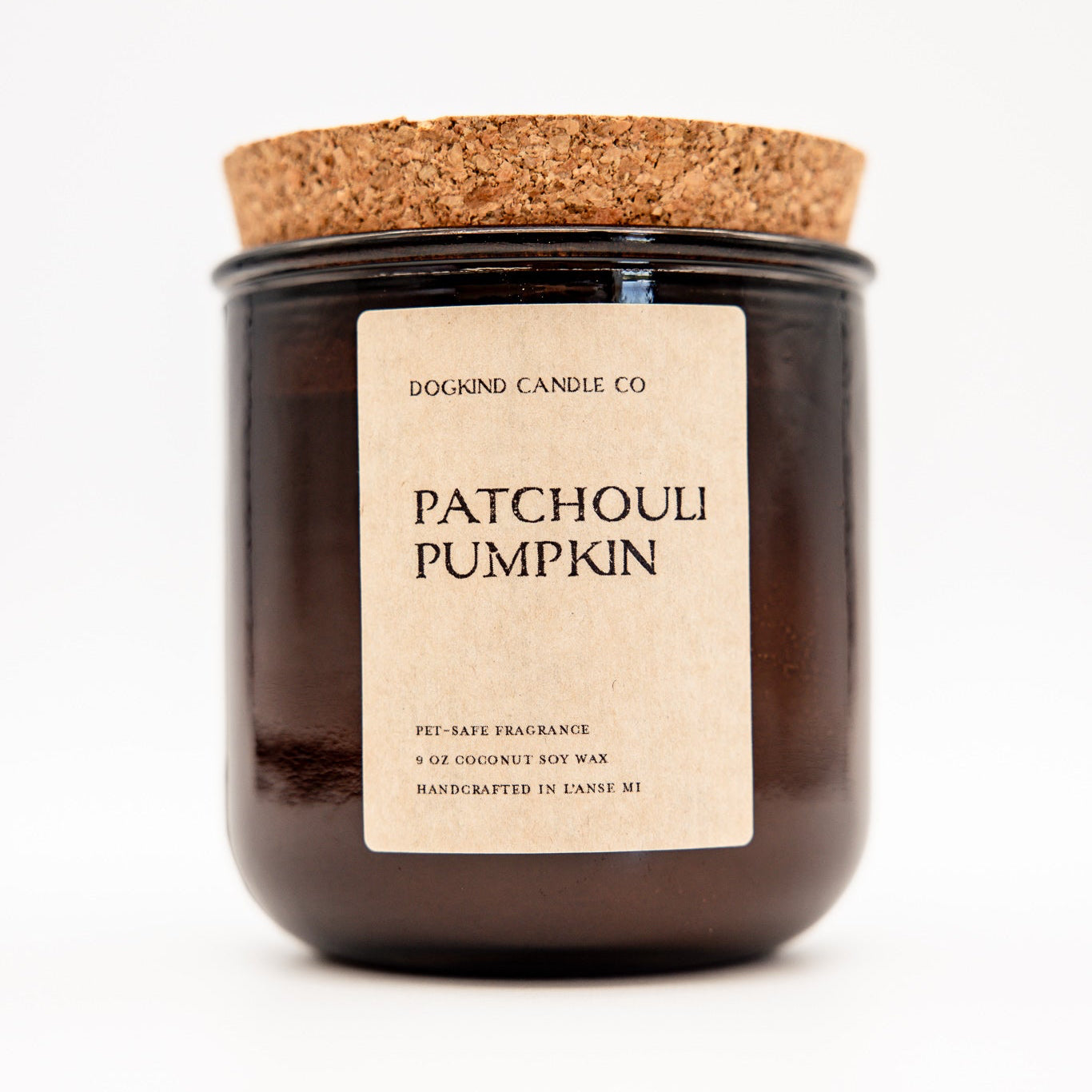 
                  
                    A dark amber glass jar candle with a cork lid and a beige paper label reading 'DOGKIND CANDLE CO. PATCHOULI PUMPKIN' on a white background.
                  
                