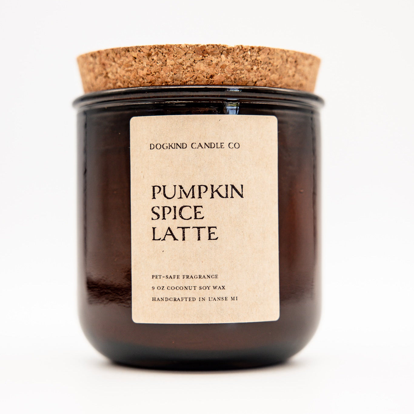 A Dogkind Candle Co. 'Pumpkin Spice Latte' soy wax candle in a dark amber glass jar with a cork lid and a beige paper label, set against a plain white background.