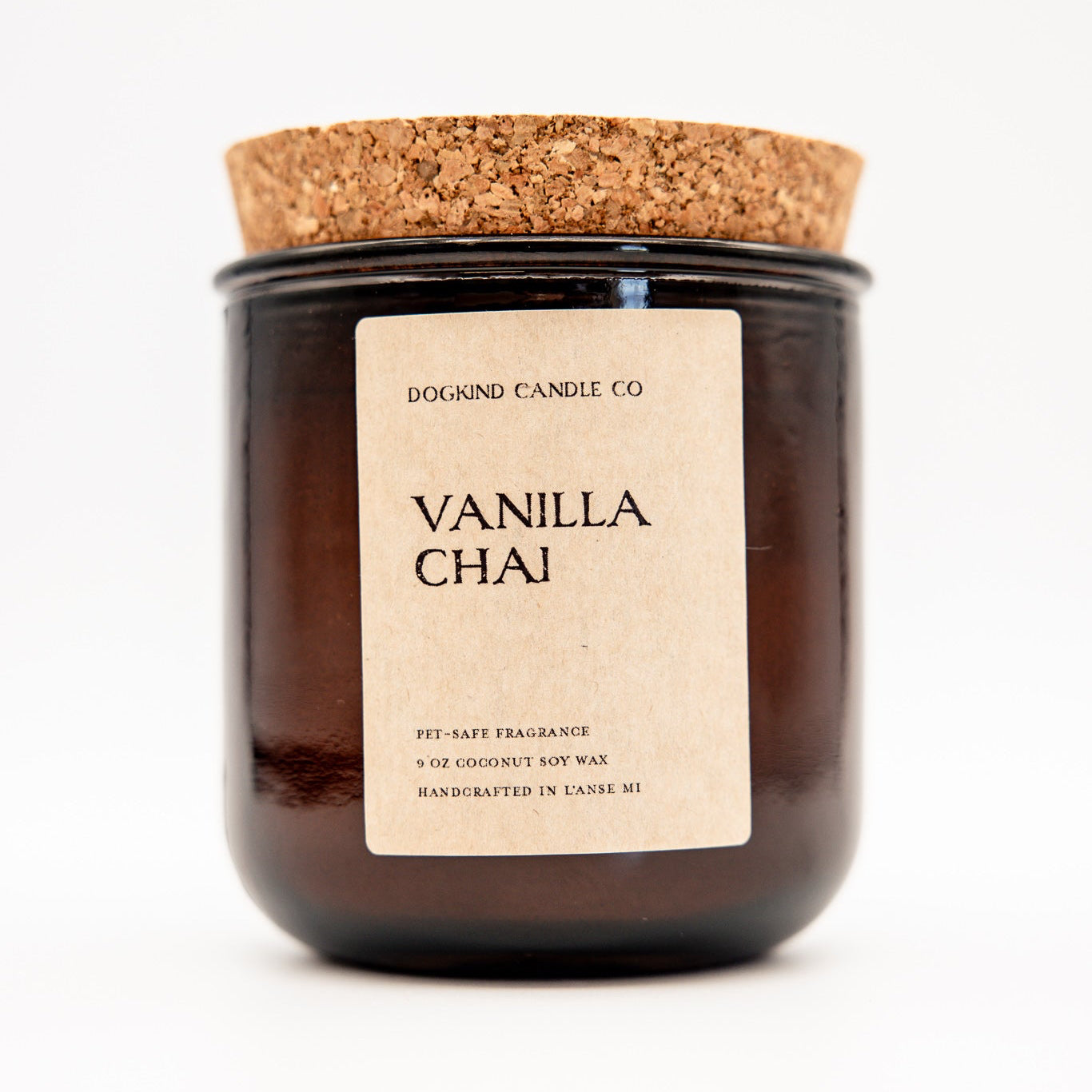 A Dogkind Candle Co. Vanilla Chai scented soy wax candle in a dark amber glass jar with a cork lid and a beige paper label, set against a plain white background.