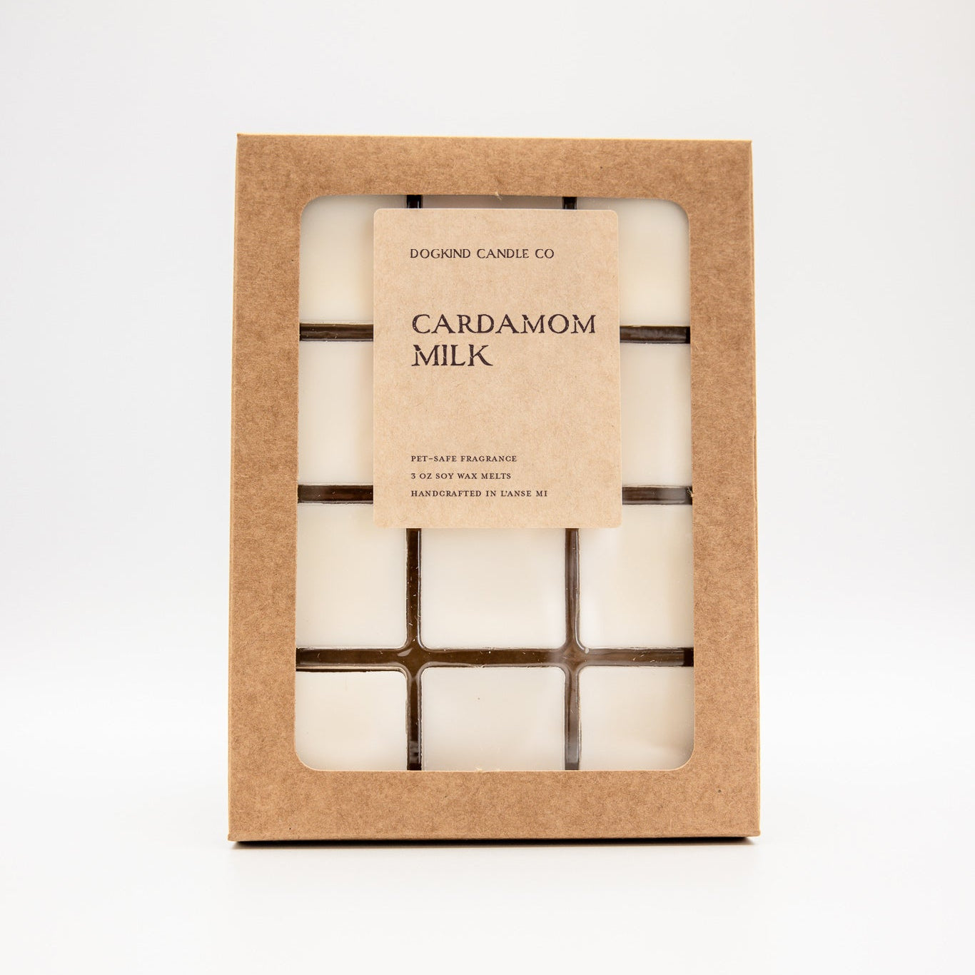 A square kraft paper box containing 3 oz soy wax melts with a clear window and a beige label reading 'DOGKIND CANDLE CO. CARDAMOM MILK'.
